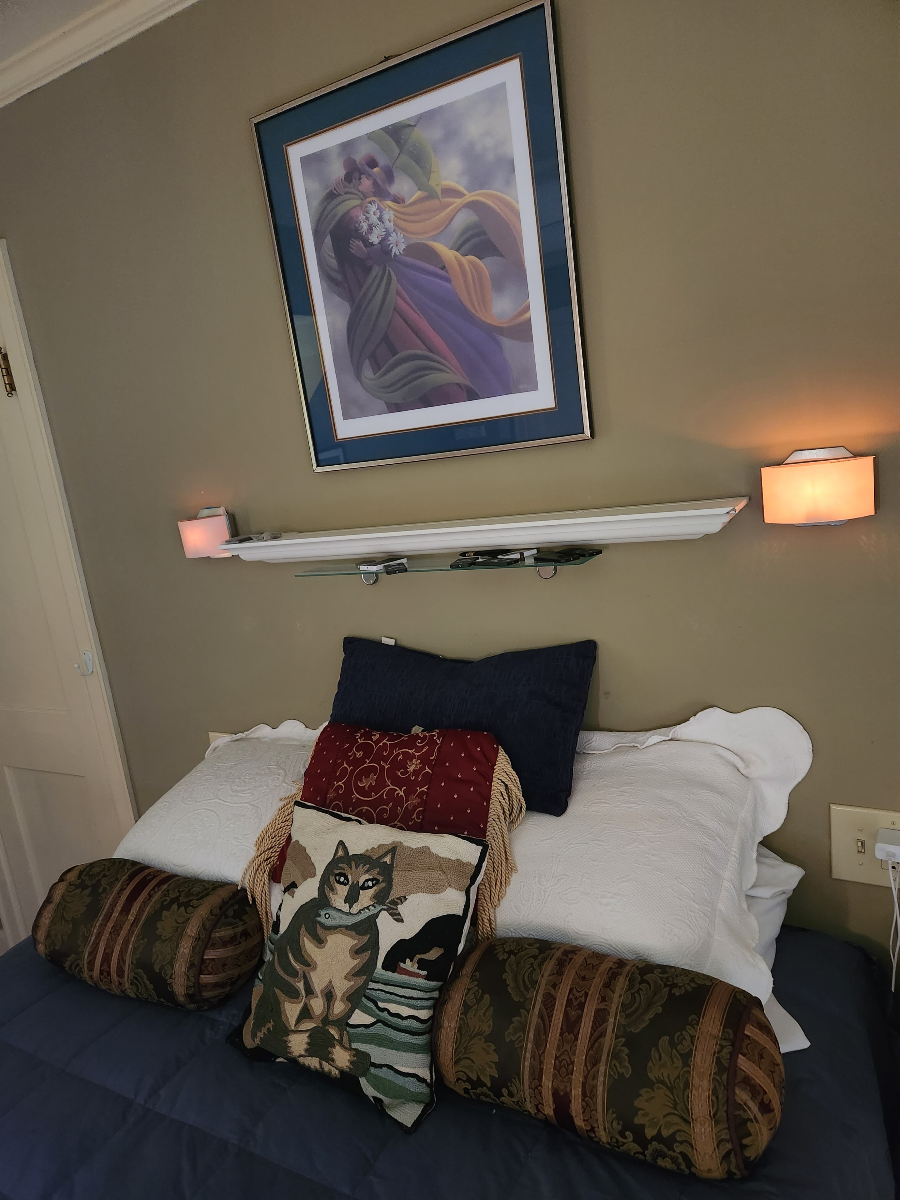 Bedroom interior with pillows, wall lighting, and framed artwork